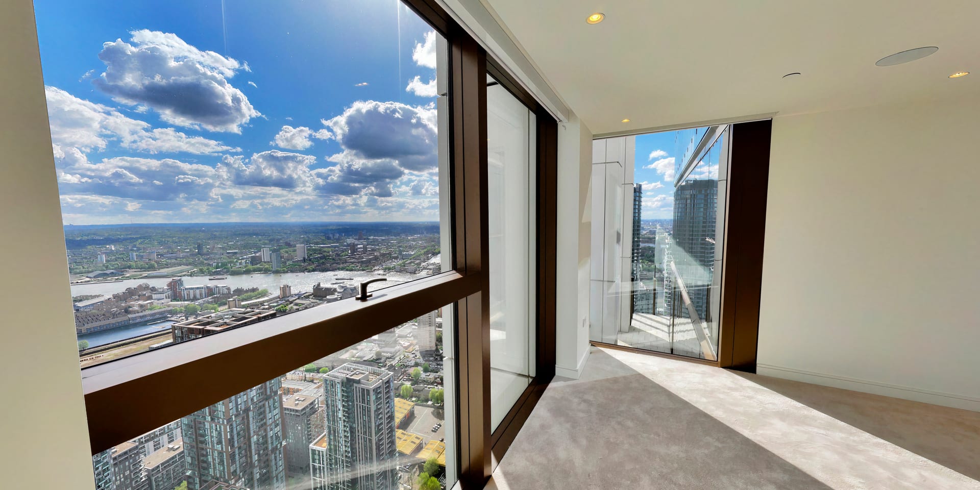 Open plan living space with herringbone parquet floors and floor-to-ceiling glass doors to the terrace
